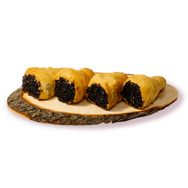 Четири шамброни с бели кремове и шоколадови пръчици на дървена поставка.